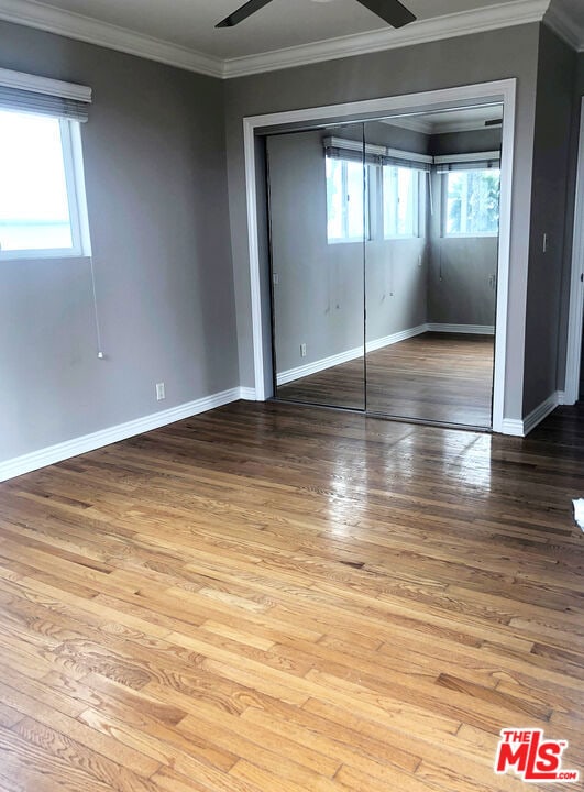 unfurnished bedroom with hardwood / wood-style floors and multiple windows