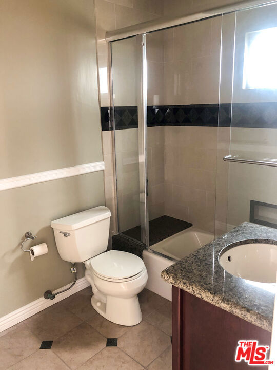 full bathroom with tile patterned flooring, vanity, toilet, and bath / shower combo with glass door