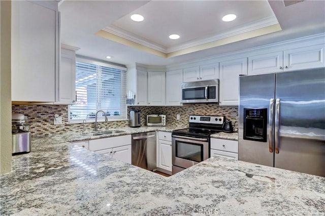 kitchen with white cabinets, stainless steel appliances, a raised ceiling, and sink