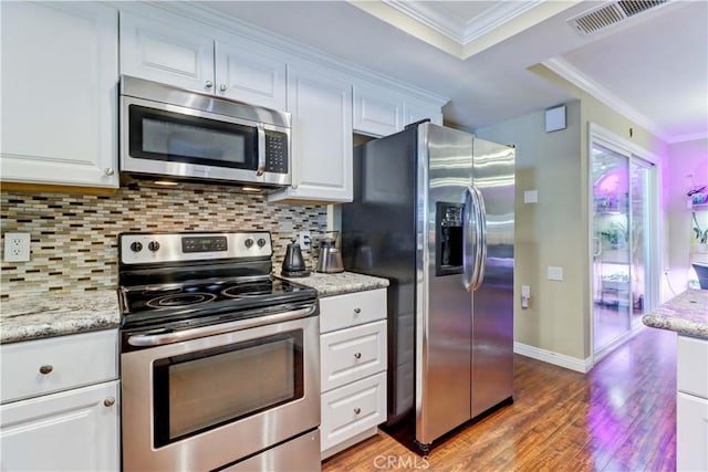 kitchen with white cabinets, ornamental molding, backsplash, light stone countertops, and appliances with stainless steel finishes