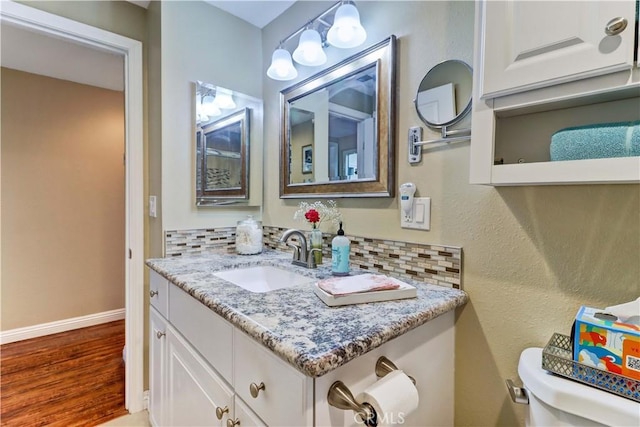 bathroom featuring toilet, vanity, hardwood / wood-style floors, and decorative backsplash