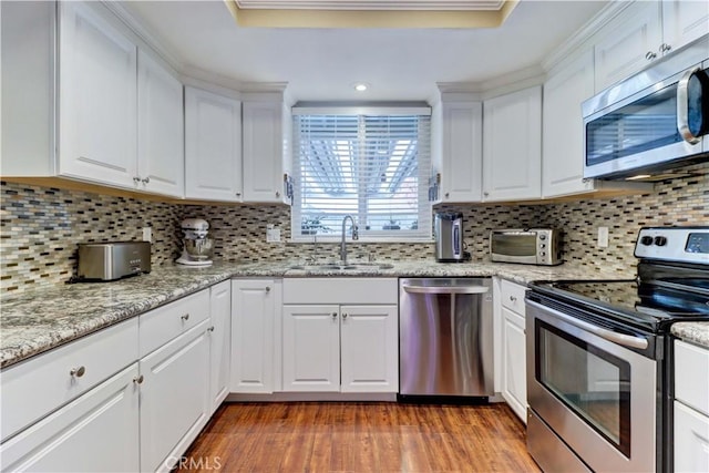 kitchen featuring sink, stainless steel appliances, white cabinetry, and tasteful backsplash