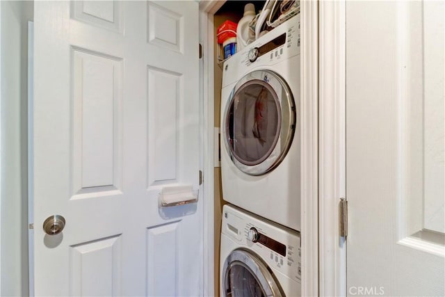 clothes washing area with stacked washing maching and dryer