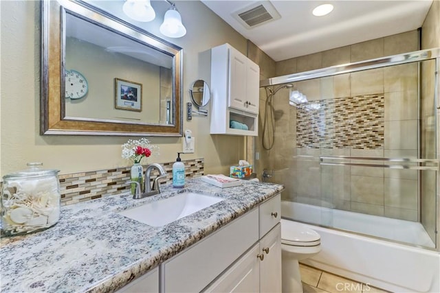 full bathroom with tile patterned flooring, bath / shower combo with glass door, vanity, and toilet