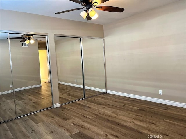 unfurnished bedroom featuring two closets, dark wood-type flooring, and ceiling fan