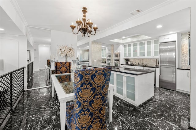 kitchen featuring ornamental molding, stainless steel built in refrigerator, a kitchen island, an inviting chandelier, and white cabinetry