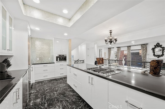 kitchen featuring tasteful backsplash, stainless steel appliances, decorative light fixtures, a notable chandelier, and white cabinetry