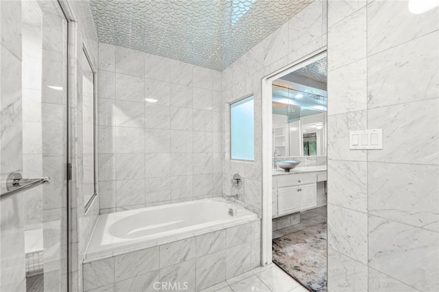 bathroom featuring plus walk in shower, vanity, and tile walls