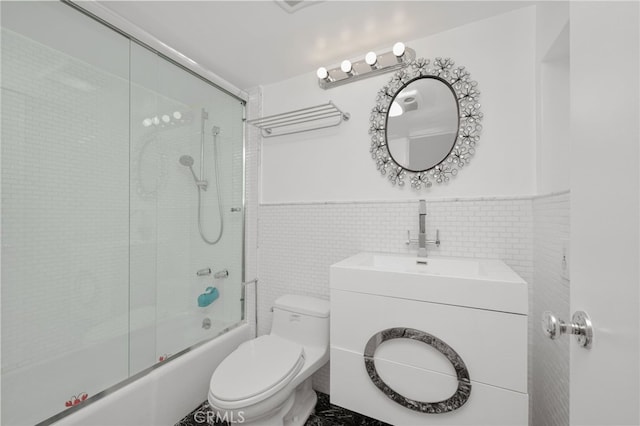 full bathroom with vanity, toilet, tile walls, and bath / shower combo with glass door