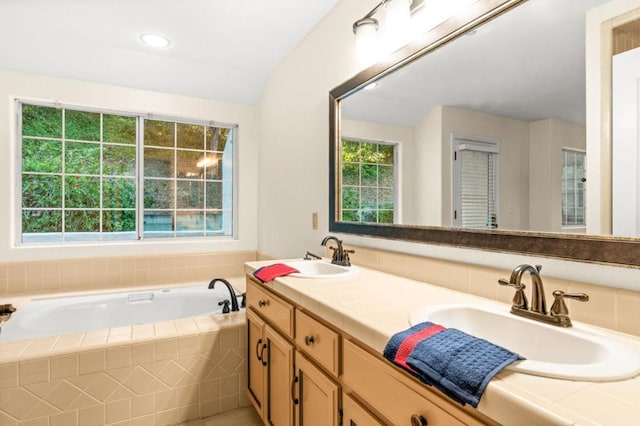 bathroom featuring tiled tub, vanity, and lofted ceiling