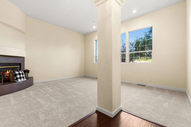 unfurnished living room featuring ornate columns, carpet, and a fireplace