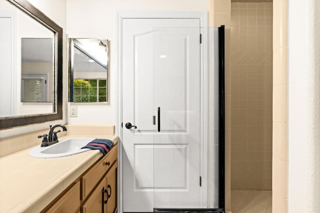 bathroom featuring a tile shower and vanity