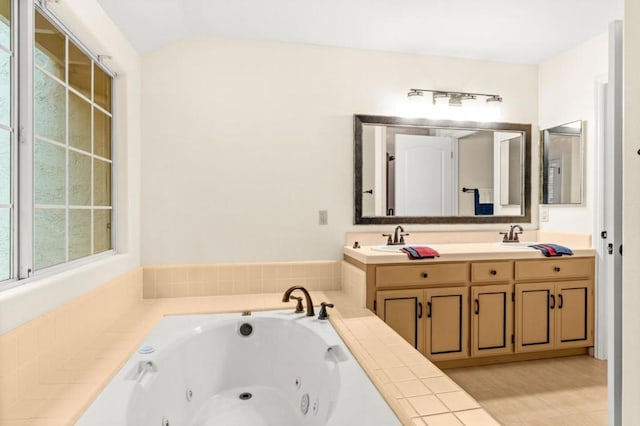 bathroom with a relaxing tiled tub, vanity, and vaulted ceiling