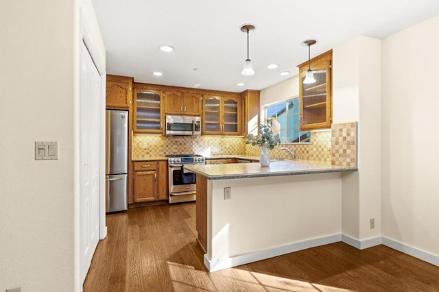 kitchen featuring pendant lighting, dark hardwood / wood-style flooring, stainless steel appliances, and kitchen peninsula