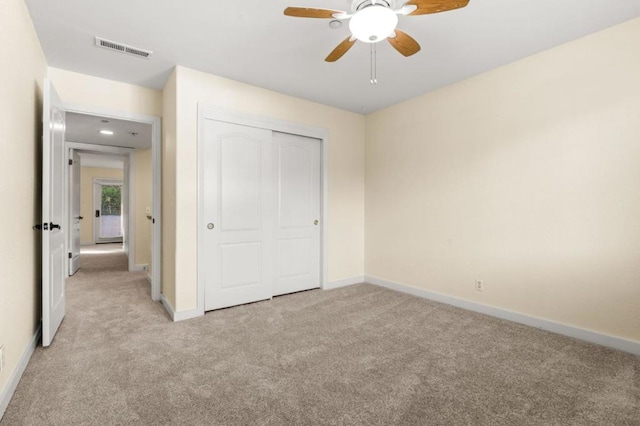 unfurnished bedroom with light colored carpet, a closet, and ceiling fan