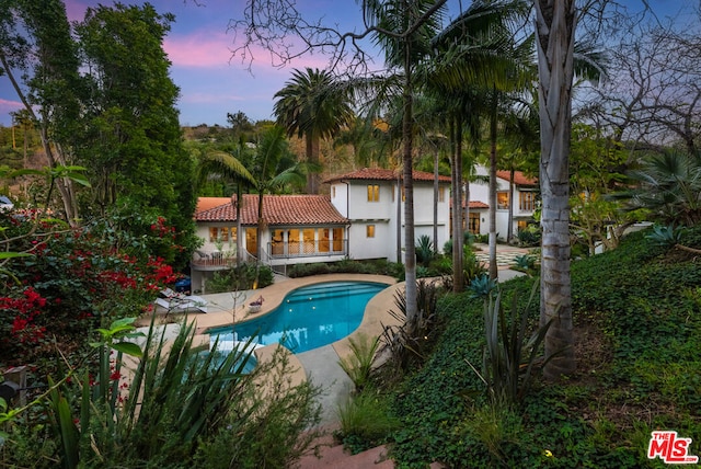 pool at dusk featuring a patio