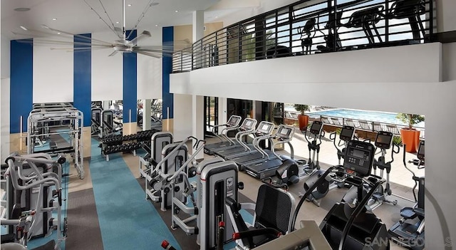 exercise room featuring ceiling fan and a towering ceiling