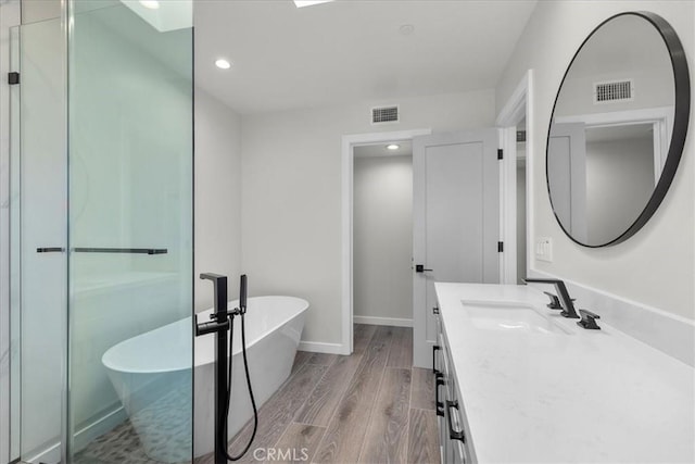 bathroom featuring wood-type flooring, vanity, and a tub to relax in