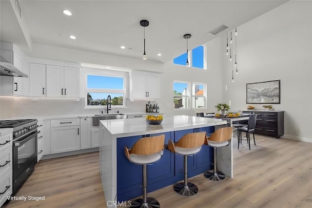 kitchen with sink, white cabinetry, black gas range oven, and light hardwood / wood-style flooring