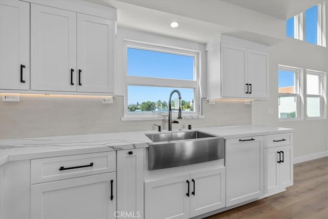 kitchen with light hardwood / wood-style flooring, white cabinetry, a wealth of natural light, and sink