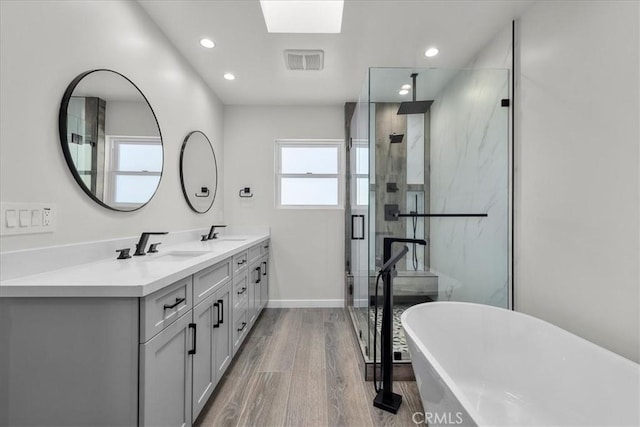 bathroom with wood-type flooring, vanity, a skylight, and independent shower and bath