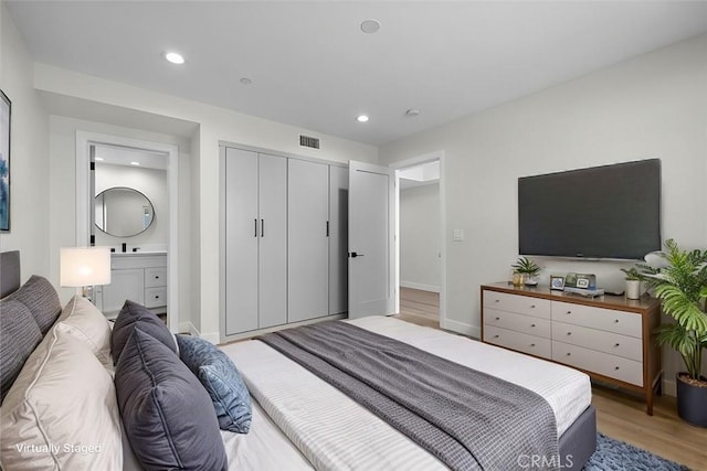 bedroom featuring light hardwood / wood-style flooring, connected bathroom, and a closet