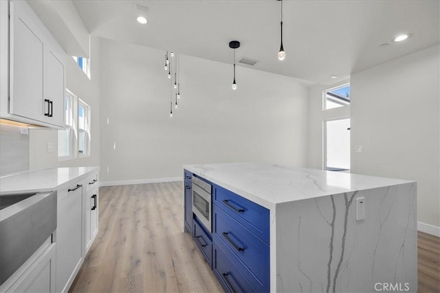 kitchen featuring light stone countertops, pendant lighting, white cabinetry, and plenty of natural light