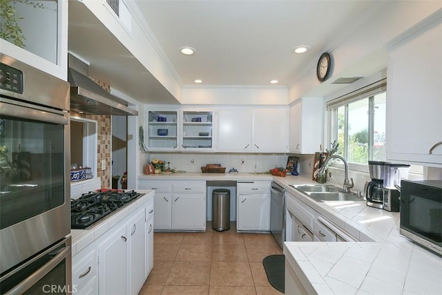 kitchen with appliances with stainless steel finishes, tasteful backsplash, sink, tile countertops, and white cabinetry