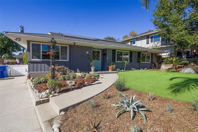 view of front of house featuring a front yard and solar panels