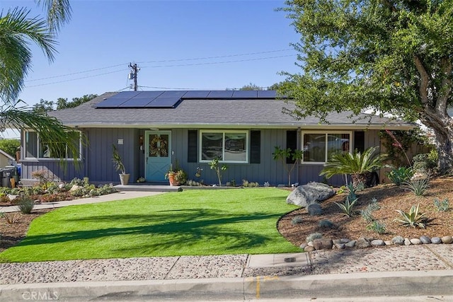 ranch-style house featuring a front lawn and solar panels