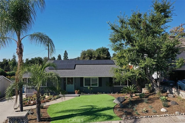 ranch-style house featuring solar panels and a front lawn