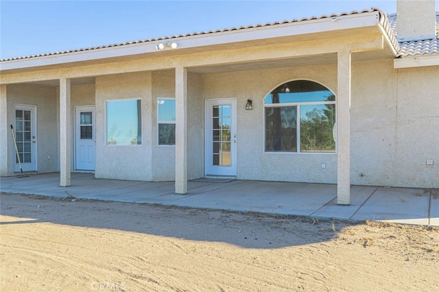 view of exterior entry with a patio area