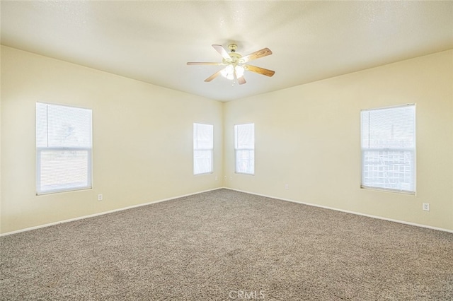 spare room with carpet flooring, a wealth of natural light, and ceiling fan