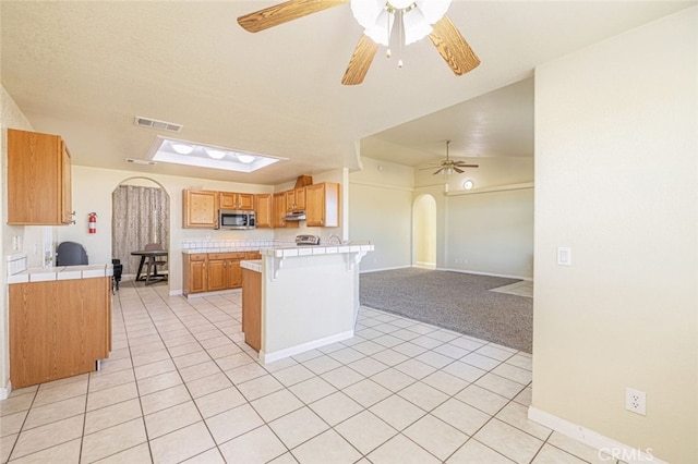 kitchen featuring kitchen peninsula, light carpet, vaulted ceiling, and a breakfast bar area