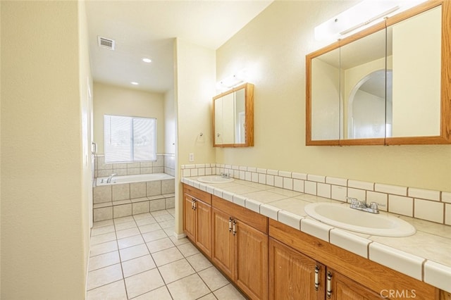 bathroom with tile patterned flooring, vanity, and a relaxing tiled tub