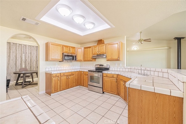 kitchen with light tile patterned flooring, appliances with stainless steel finishes, tile counters, and ceiling fan