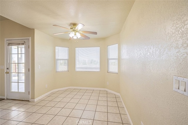 spare room featuring ceiling fan, light tile patterned floors, and a textured ceiling