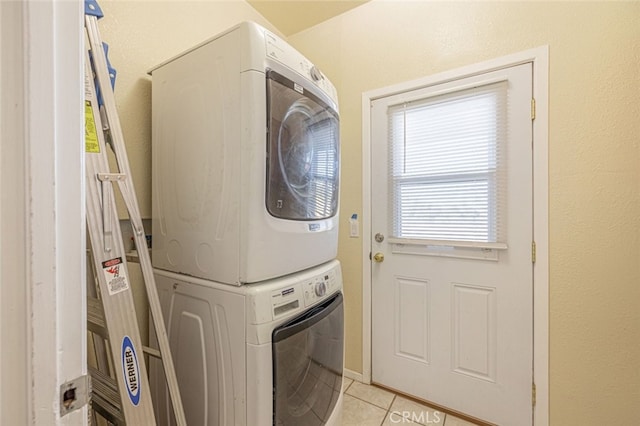 clothes washing area featuring light tile patterned floors and stacked washer and dryer