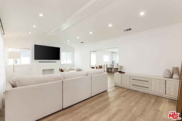 living room featuring lofted ceiling with beams, a healthy amount of sunlight, and light wood-type flooring