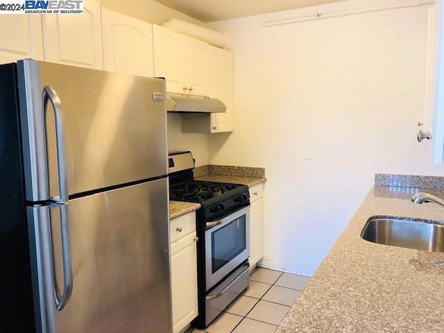 kitchen featuring white cabinetry, sink, light tile patterned flooring, and appliances with stainless steel finishes