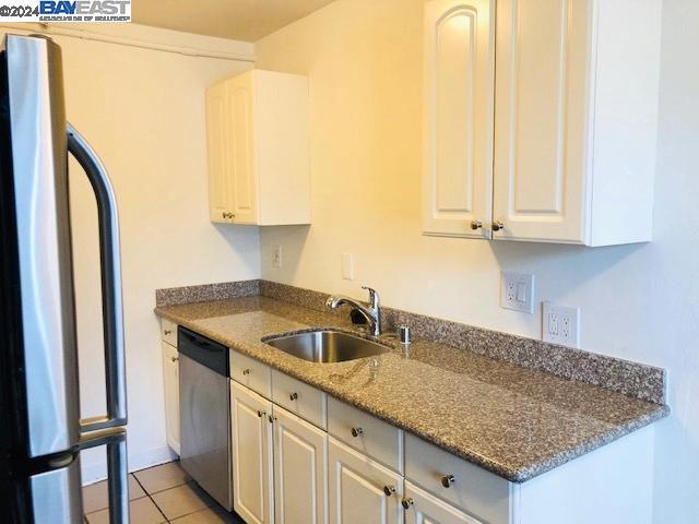 kitchen featuring white cabinets, appliances with stainless steel finishes, light tile patterned flooring, and sink