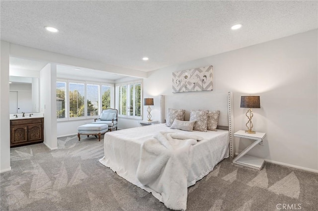 bedroom featuring sink, connected bathroom, carpet, and a textured ceiling