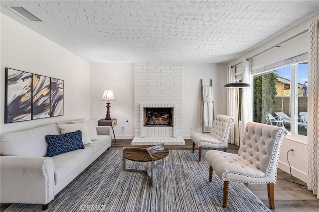 living room featuring a brick fireplace, a textured ceiling, and a wealth of natural light