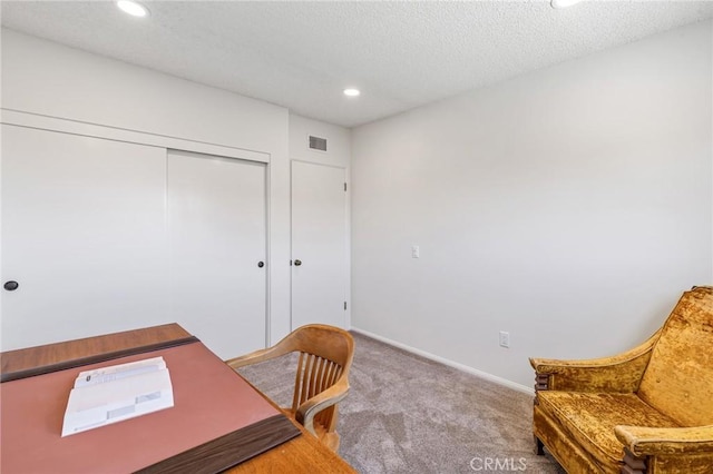 carpeted office featuring a textured ceiling