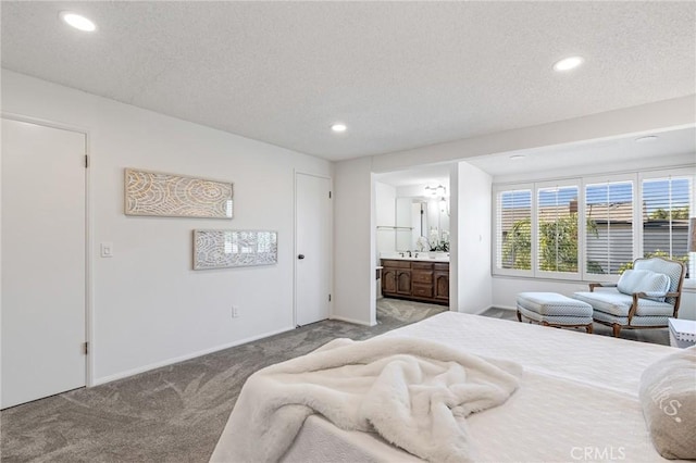 bedroom with a textured ceiling, ensuite bathroom, and light carpet