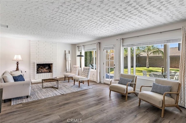 living room featuring a fireplace, hardwood / wood-style floors, a healthy amount of sunlight, and a textured ceiling