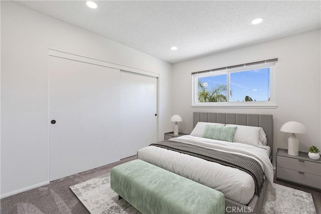 carpeted bedroom with a textured ceiling and a closet