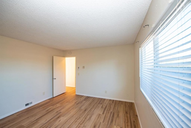 spare room with light hardwood / wood-style floors and a textured ceiling