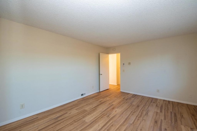 unfurnished room with a textured ceiling and light hardwood / wood-style flooring