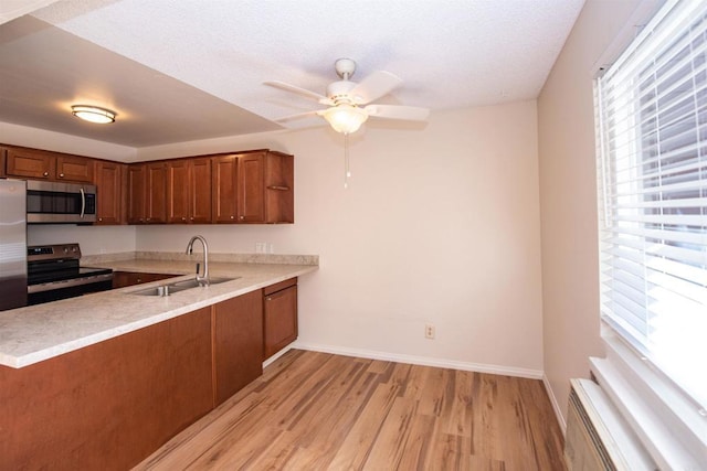 kitchen featuring kitchen peninsula, light wood-type flooring, range with electric cooktop, ceiling fan, and sink